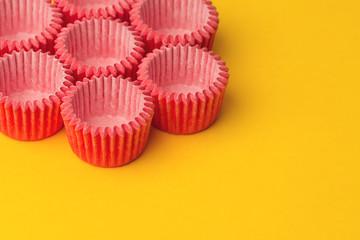 arrangement of pink small cupcake tray holders on yellow