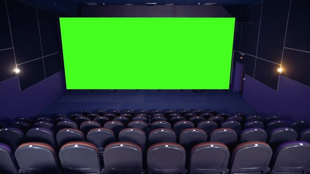 Dark empty cinema hall with green screen.
