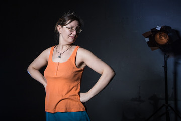 Obraz premium Woman in a yellow t-shirt in a dark Studio illuminated by colored spotlights