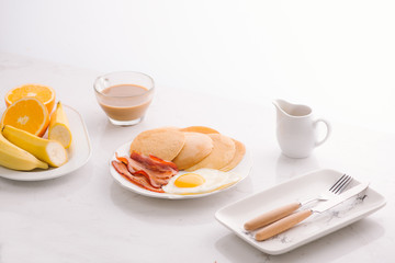 Breakfast plate with pancakes, eggs, bacon and fruit.