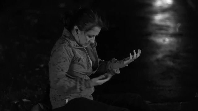 A woman suffers an injury at the side of the road and uses her cell phone to call for help.