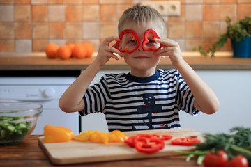 Happy boy having fun with food vegetables at kitchen