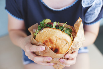 The girl is holding a big hamburger