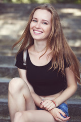 Fototapeta premium young girl in shorts, sits on the steps. emotional portrait.