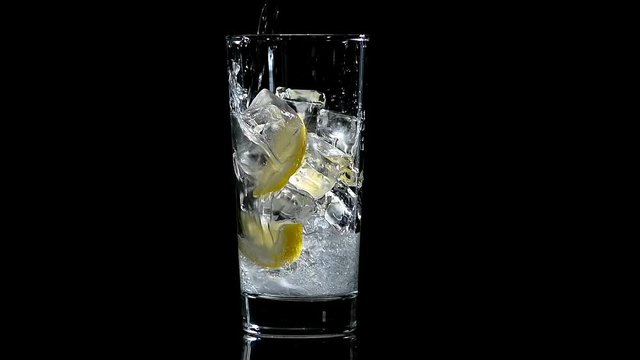 water with lemon and ice in a glass on a black isolated background