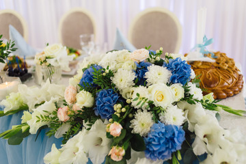 The wedding table of the newlyweds is decorated with bouquets of fresh flowers