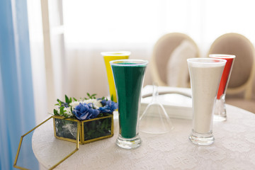 several glasses of sand of different colors are on the table
