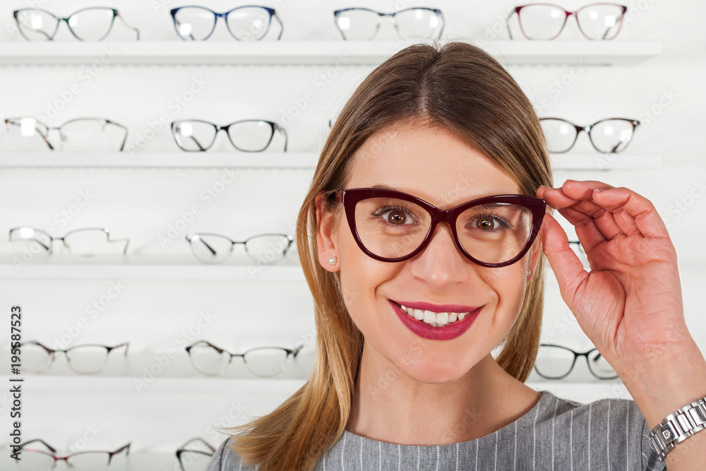 Wall mural Young woman choosing eyeglass frame