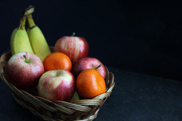 Dark Food - Chiaroscuro mixed fruit in wicker basket with dark background with copy space right