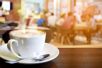 Cappuccino on the table with blur people at cafe background