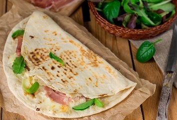 Italian flatbread piadina with prosciutto ham and mozzarella cheese