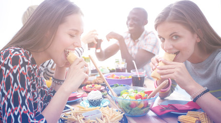 Top view of group of people having dinner together while sitting at wooden table. Food on the table. People eat fast food.
