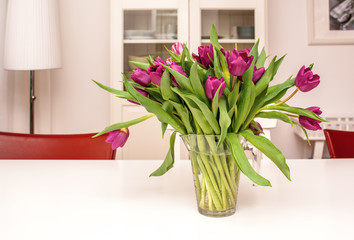 Purple tulips in a glass vase in bright living room