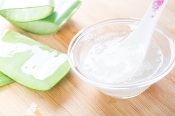 Fresh aloe vera leaves with aloe vera juice in glass bowl on wooden background