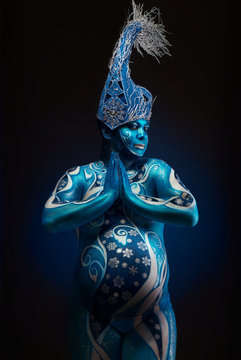 Beautiful pregnant woman with headwear and abstract body art in shades of blue and white