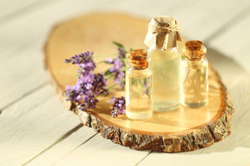 Obraz na płótnie Canvas Essential lavender oil. Lavender oil set in glass transparent bottles and sprigs of fresh lavender on a wooden cut on a gray background.Pure Organic Oil. Botanical cosmetic