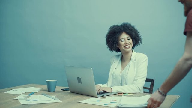 Young african american woman in an office, working,talking on the phone and communicating with her coworker