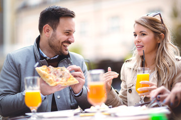 Beautiful loving couple sitting in outdoor cafe and eating pizza. Lifestyle concept