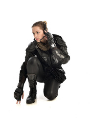 full length portrait of female  soldier wearing black  tactical armour, seated pose, isolated on white studio background.
