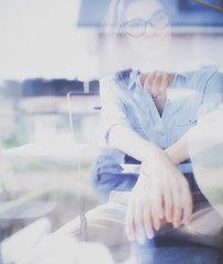 Young woman sitting at office table with laptop,view through window. Young woman