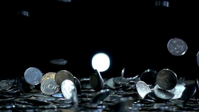 Slow motion, a pile of coins falls on a wooden table on a black background. Ukrainian coins in denomination of five kopecks are falling into a heap