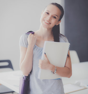 Portrait of young student woman holding exercise books. Student woman