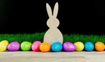 Fototapeta na wymiar Easter bunny with colorful eggs , green meadow and black background, copy space