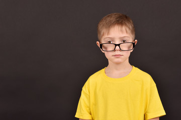 A boy in glasses. A child's portrait on a black background.