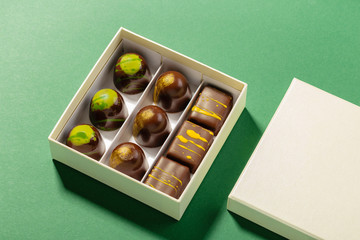 Assortment of luxury bonbons in box on green background