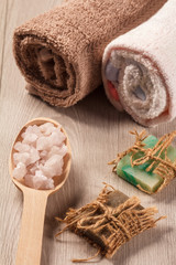 Wooden spoon with white sea salt and handmade soap for bathroom procedures with towels on the background