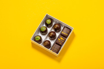Assortment of luxury bonbons in box on bright yellow background