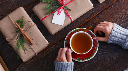 Woman sitting on the desk with christmas gift box. Hands of woman