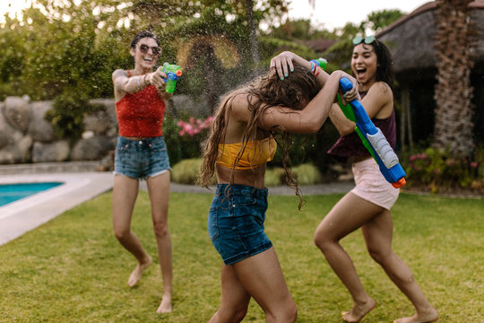 Crazy female friends having water gun battle - Powered by Adobe