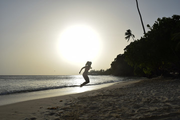 Young woman is jumping into the sunset at the beach