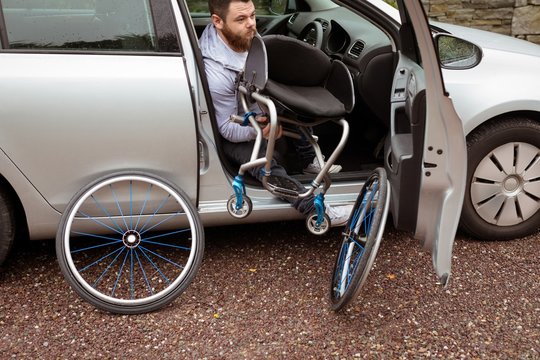 Disabled man holding wheelchair while boarding in his car