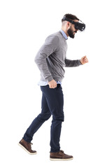 Side view of bearded man watching virtual reality glasses running and looking down. Full body isolated on white background. 