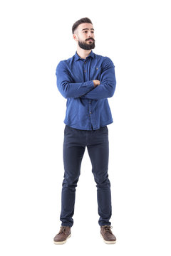 Confident cool young bearded man standing and looking away with crossed hands. Full body isolated on white background. 