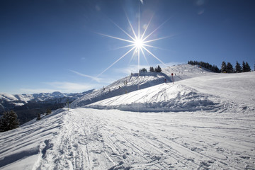 Panoramic view of ski slope in winter sunny day at the alpine ski resort. People skiing down the hill.