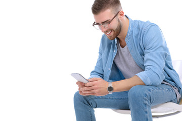Young man sitting on chair and using mobile phone. Startupper. Young entrepreneur.