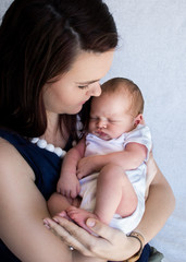Mother holding sleeping newborn baby looking at the baby