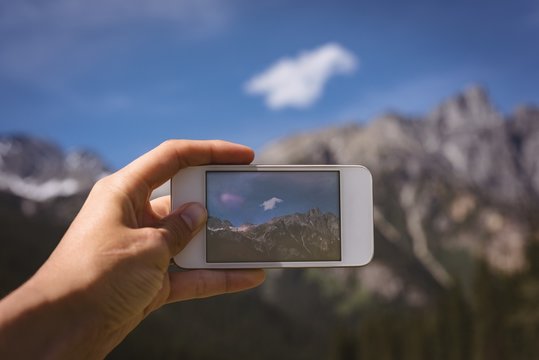 Man taking photo of mountains with mobile phone