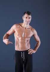 Fototapeta premium muscular man. Muscular man on a grey background showing muscles. Fitness instructor. Fitness professional. Workout. Men's fitness.