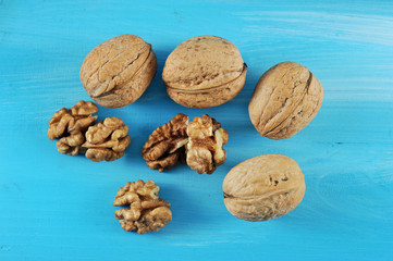 Walnuts in shell and without shell. Blue wood background. View from above. Close-up.