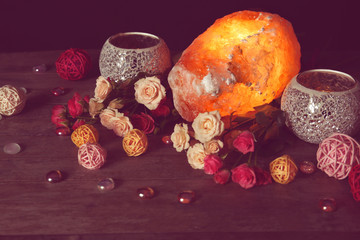 Himalayan salt lamp and flowers on wooden table