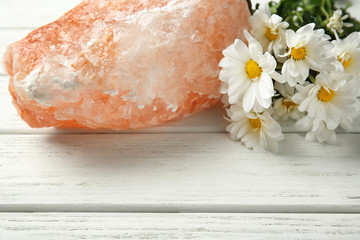 Himalayan salt lamp and flowers on wooden background