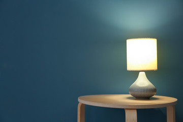 Elegant lamp on table near color wall - Powered by Adobe