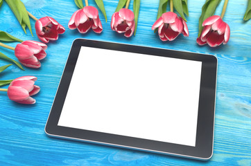 Tulip flowers and tablet computer device with blank screen on blue wooden table board background with copy space. Woman day concept. Mother day background. Saint Valentines day greeting card mock up.