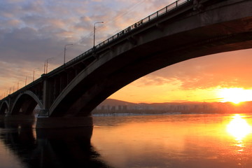 Fototapeta na wymiar Winter golden sunset over the Yenisei river in Krasnoyarsk. The sun is reflected in the mirror-like surface of the water