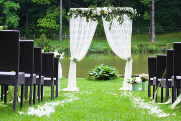 White beautiful arch decorated with flowers on wedding ceremony outdoors