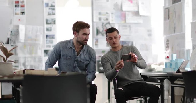 Designers looking at smartphone in creative workspace